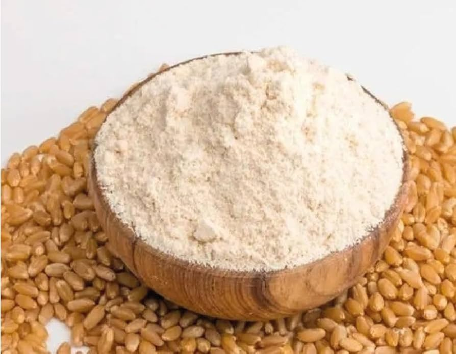 A wooden bowl of atta on wheat grains